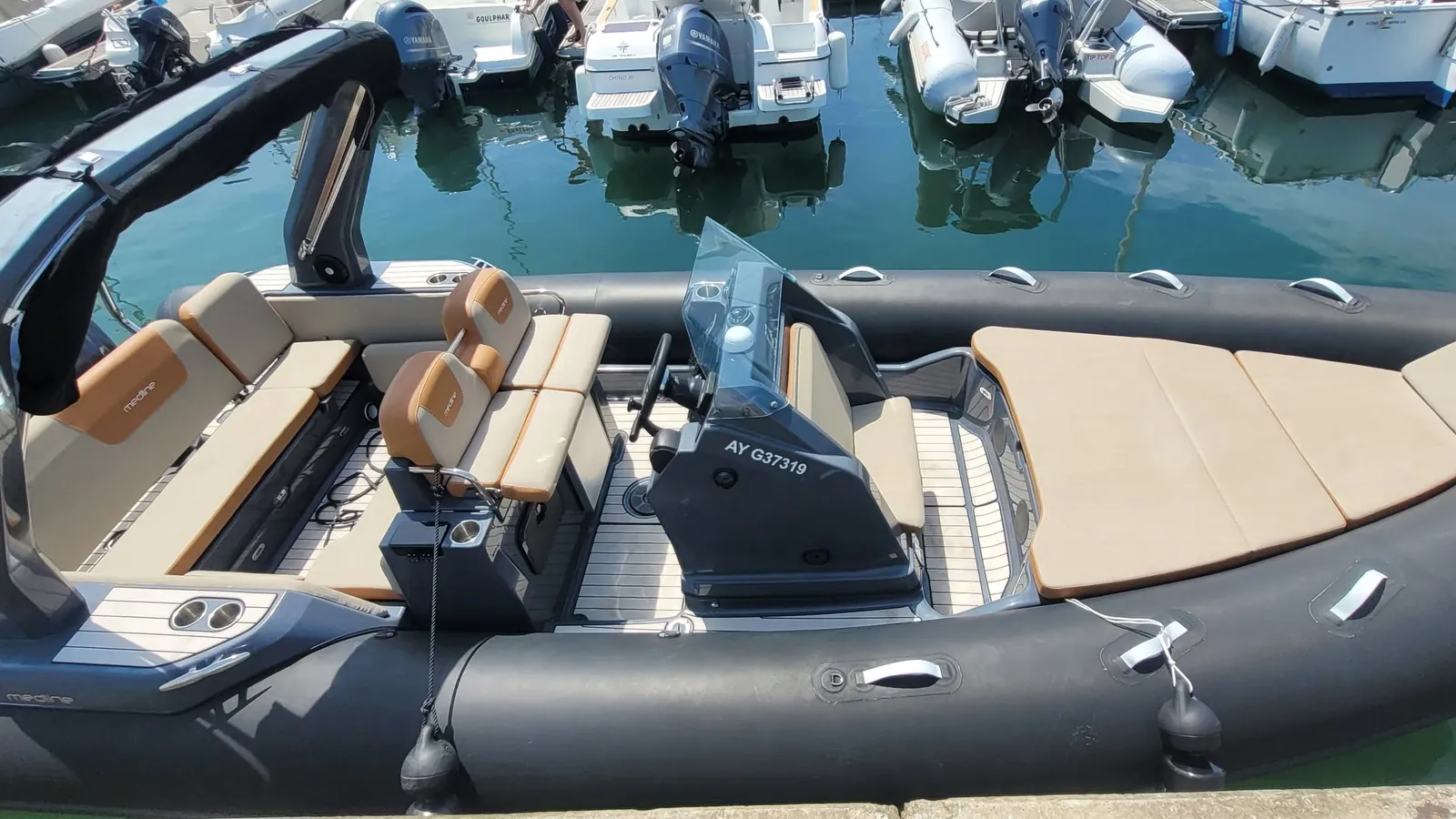 Le Gwadabreizh amarré au ponton d’un port : semi-rigide gris anthracite, sièges couleur caramel, grand bain de soleil beige à l’avant, arceau noir