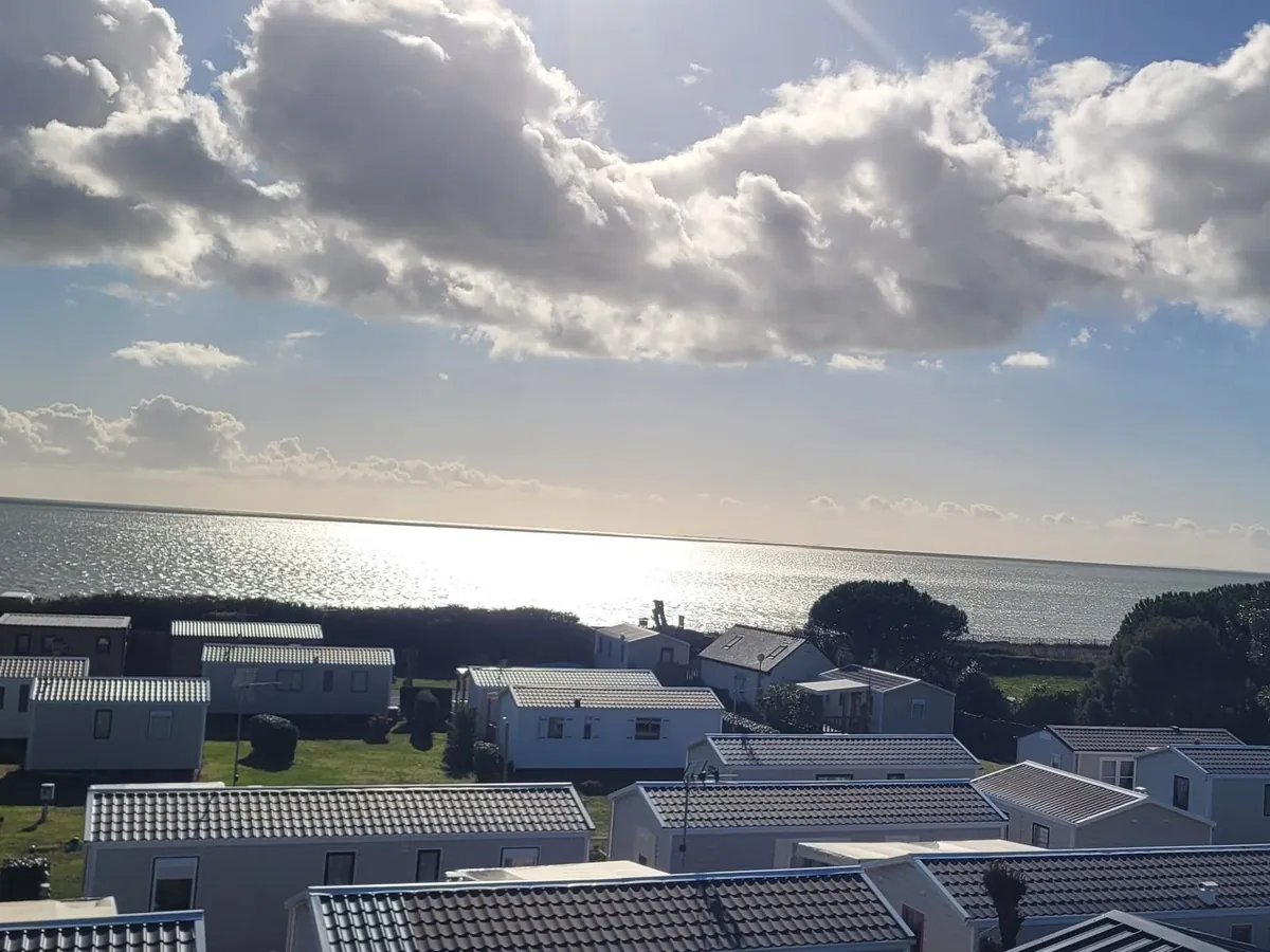 Les toits des mobil-homes du camping et, juste derrière, la mer sous un ciel nuageux