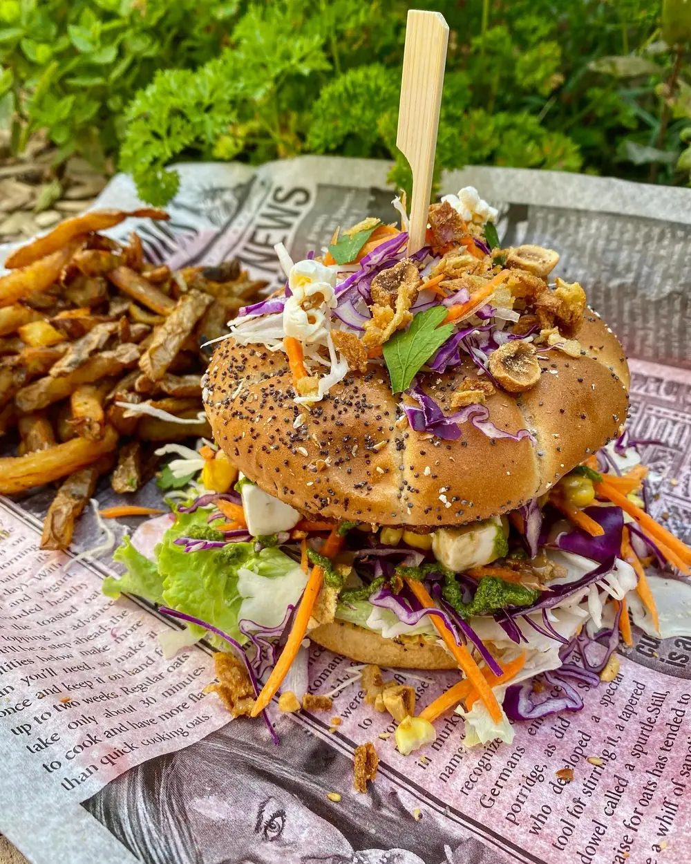 Un burger garni de salade, chou rouge, carotte et oignons croustillants, avec des frites fraîches