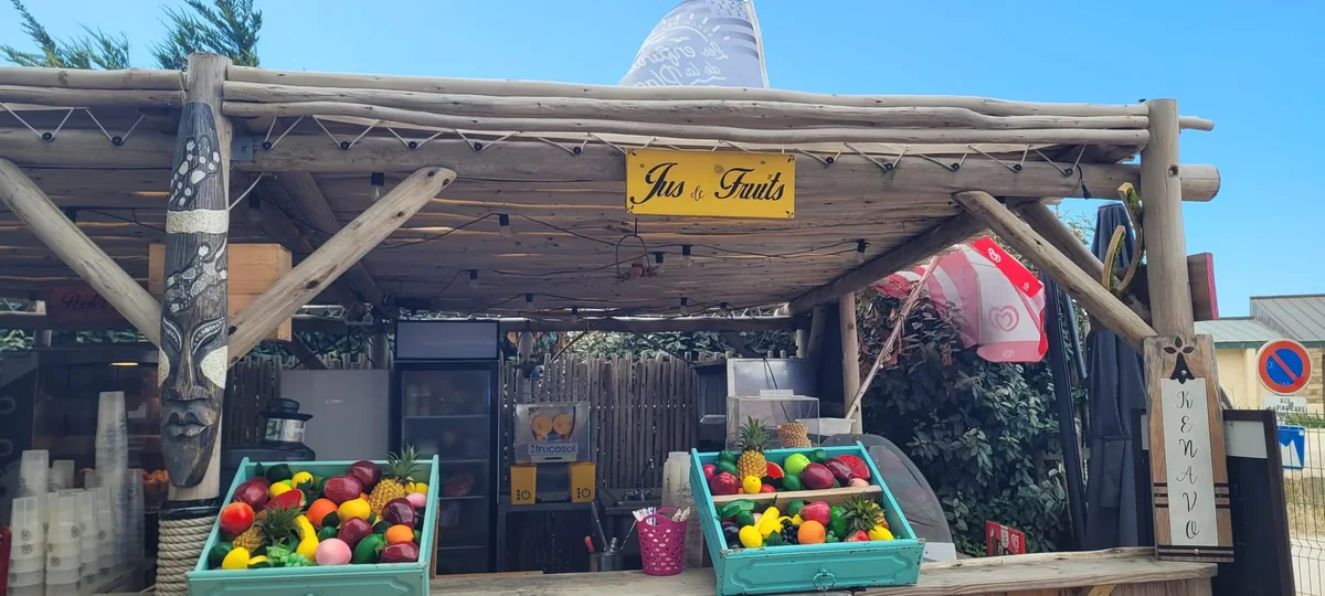 Le comptoir à jus de fruits frais de la guinguette, sous la paillote en bois tiki, avec son presse-agrumes et son enseigne Jus de Fruits