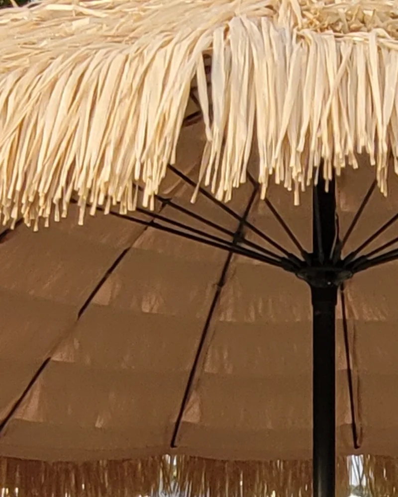 Le dessous d’un grand parasol de paille, en fin de journée