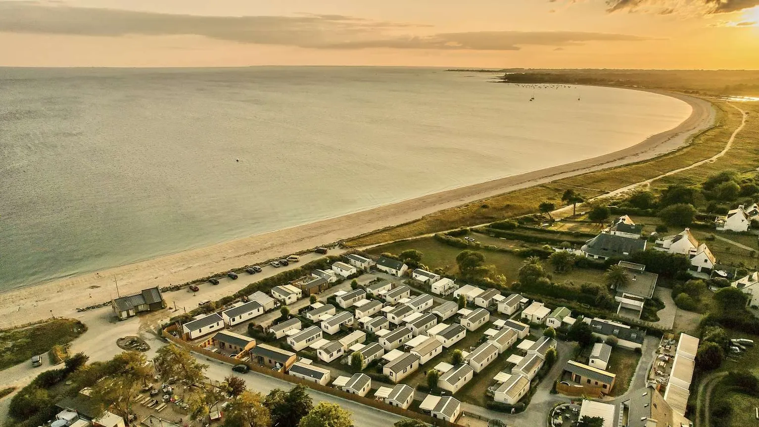 Vue aérienne de la plage de sable, de la mer et du camping, dans une lumière dorée