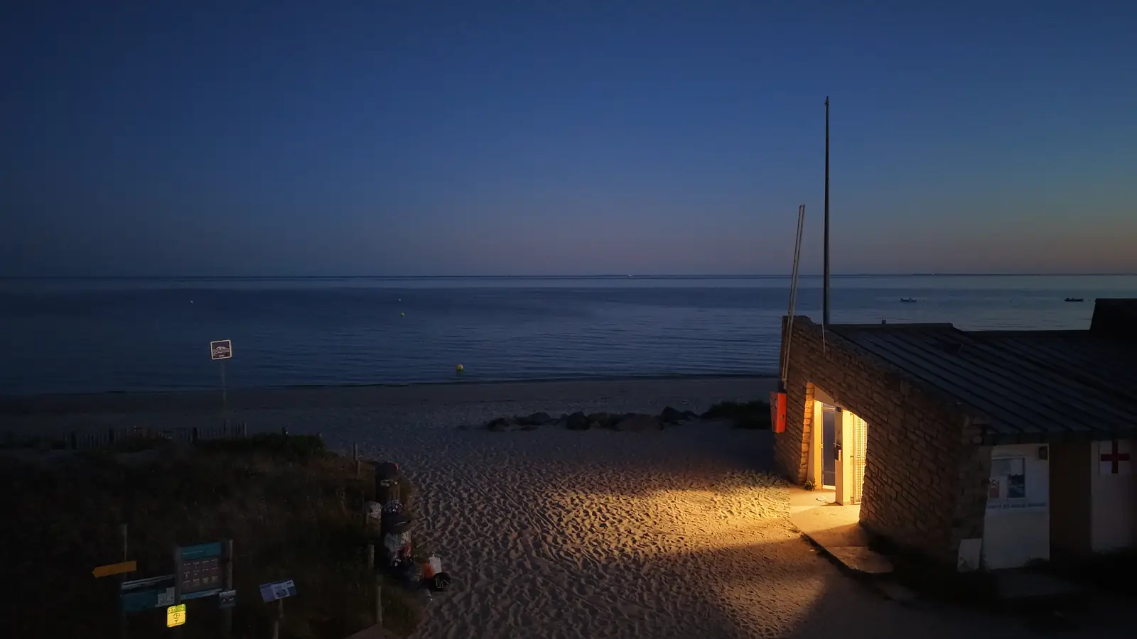 La plage à la nuit tombée, la mer calme et le poste de secours éclairé