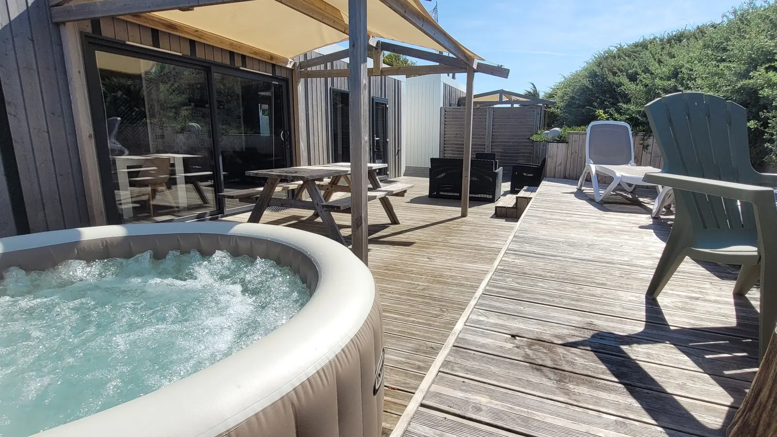 Le spa privatif, bouillonnant, sur la terrasse en bois d’un mobil-home