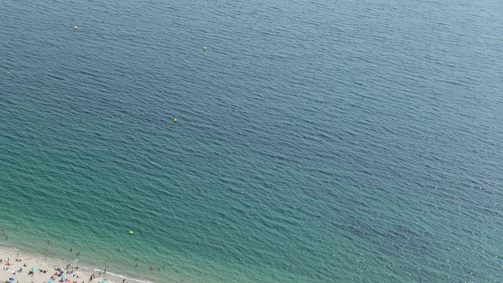 La mer turquoise au-dessus de la plage de Landrezac, vue du ciel un après-midi de juillet