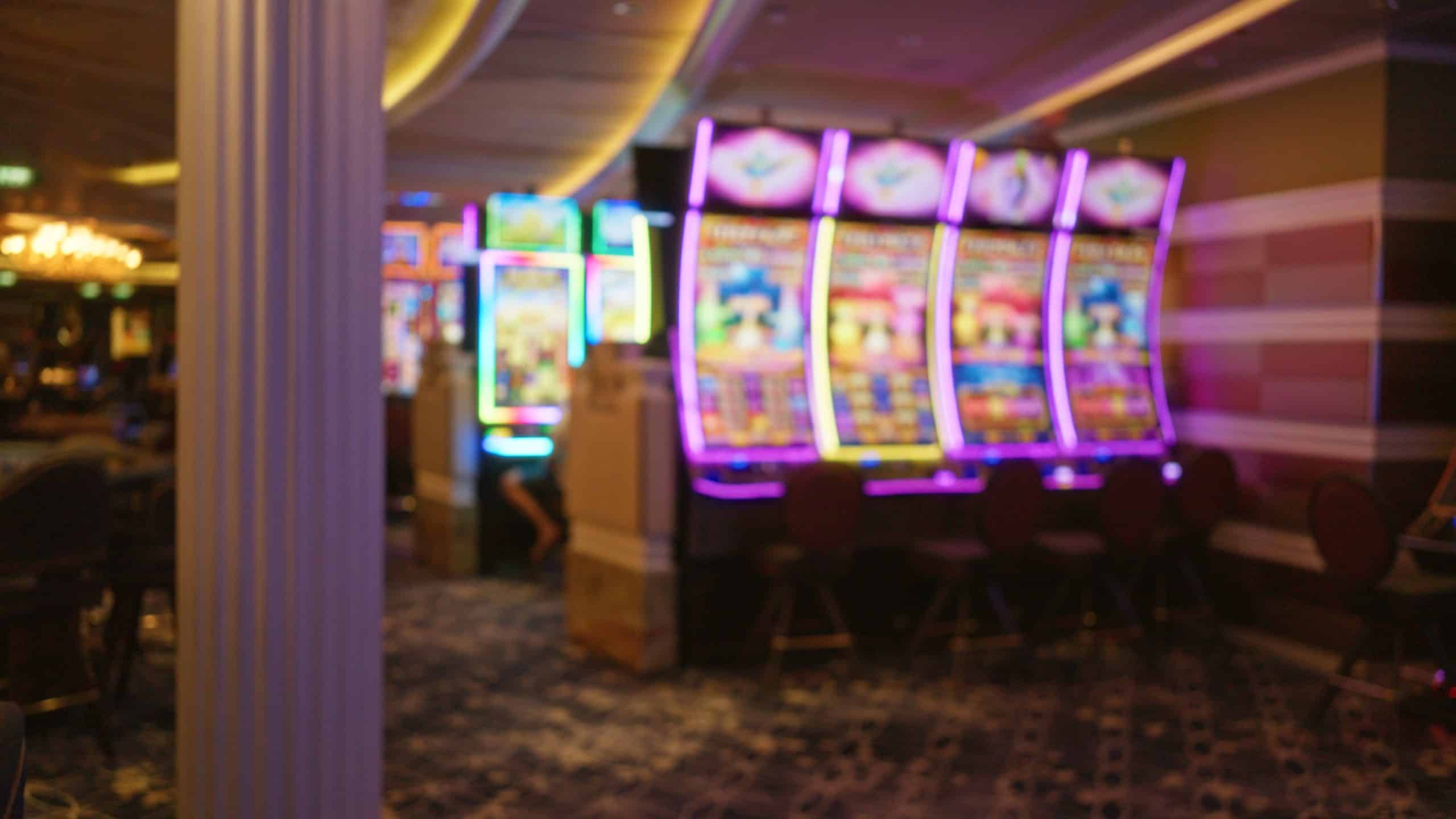 blurred slot machines with colorful lights and defocused background in a las vegas casino at night indoors.