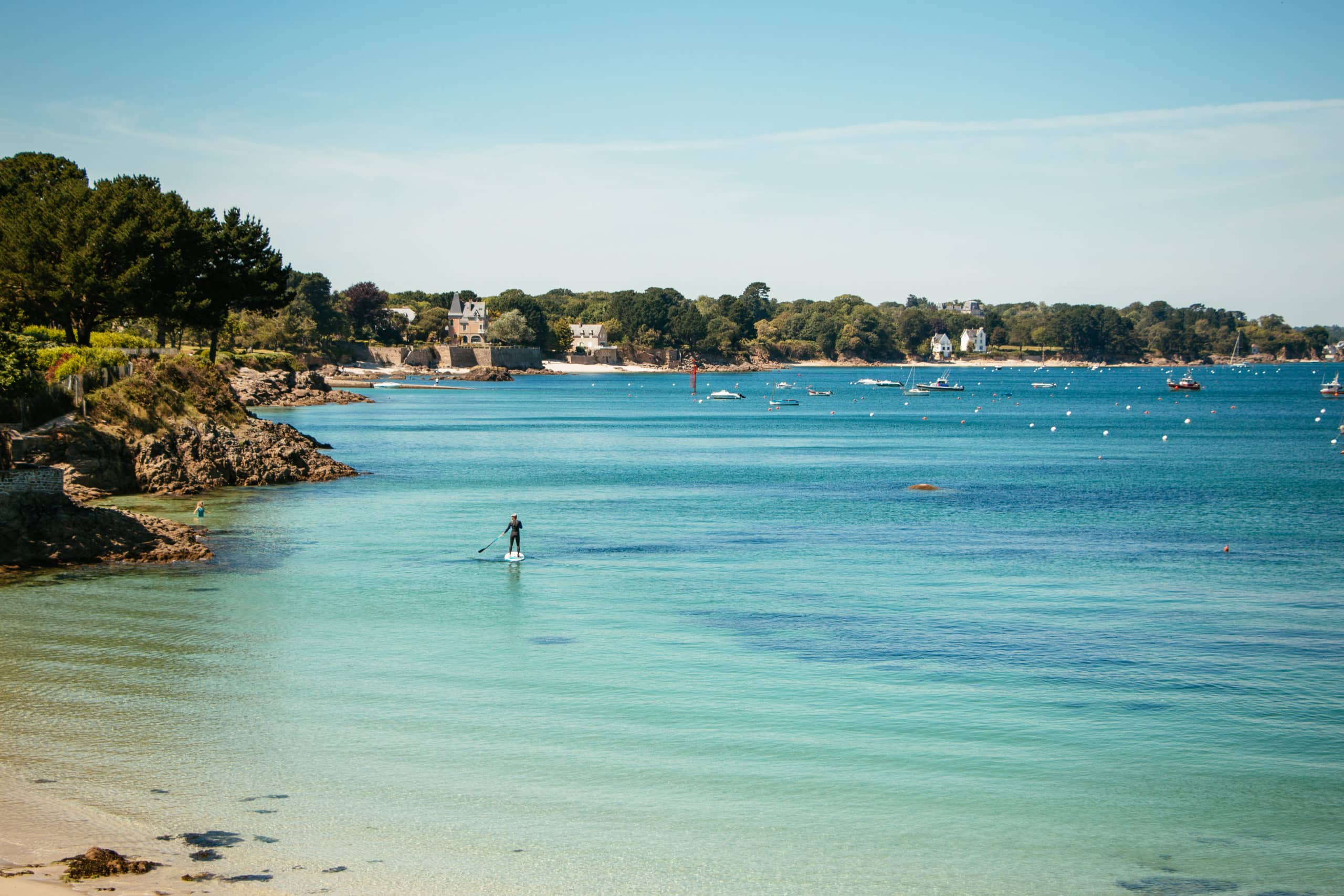 a man enjoying the seaside on is stand up paddle in beg meil, fouesnant, brittany, france